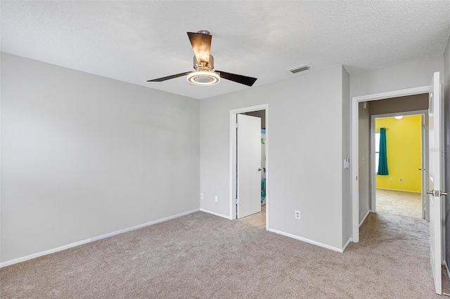 unfurnished bedroom with baseboards, visible vents, a ceiling fan, light colored carpet, and a textured ceiling