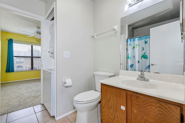 full bathroom featuring ceiling fan, tile patterned flooring, toilet, stacked washer / dryer, and vanity