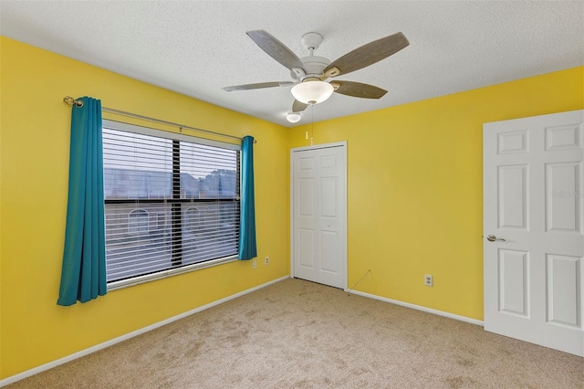 unfurnished bedroom with carpet, baseboards, ceiling fan, and a textured ceiling