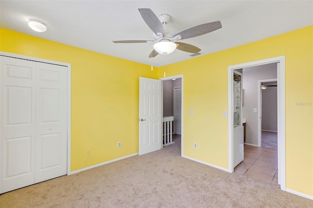 unfurnished bedroom with carpet flooring, visible vents, baseboards, a closet, and tile patterned floors