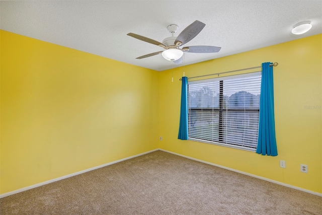 carpeted spare room featuring a textured ceiling, a ceiling fan, and baseboards