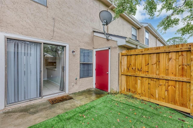 entrance to property featuring fence and stucco siding