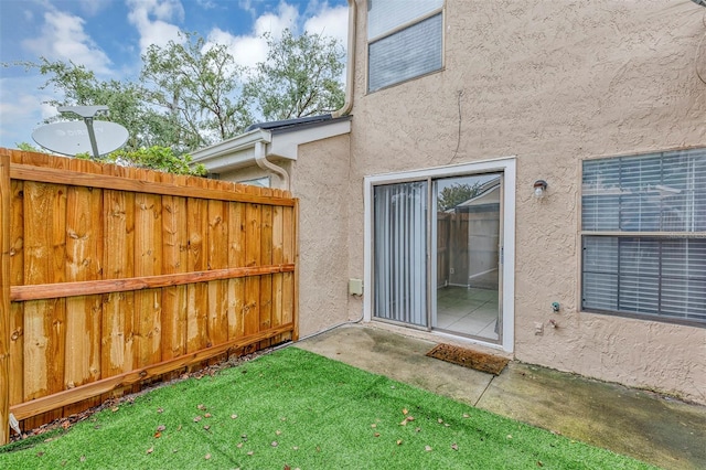 exterior space featuring fence, a lawn, and stucco siding