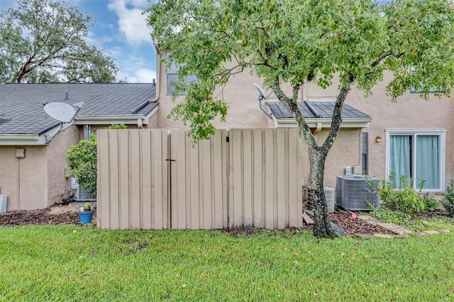 view of property exterior featuring cooling unit, a yard, fence, and stucco siding