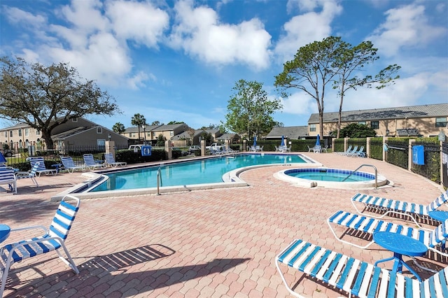 community pool featuring a patio, fence, and a hot tub