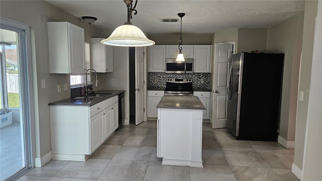 kitchen featuring appliances with stainless steel finishes, sink, white cabinets, hanging light fixtures, and a center island