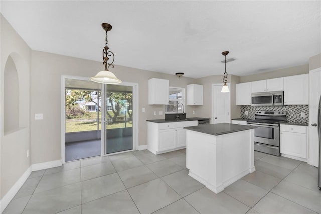 kitchen with sink, white cabinetry, stainless steel appliances, decorative backsplash, and decorative light fixtures