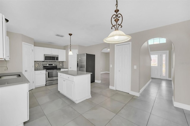 kitchen featuring pendant lighting, appliances with stainless steel finishes, a kitchen island, and white cabinets