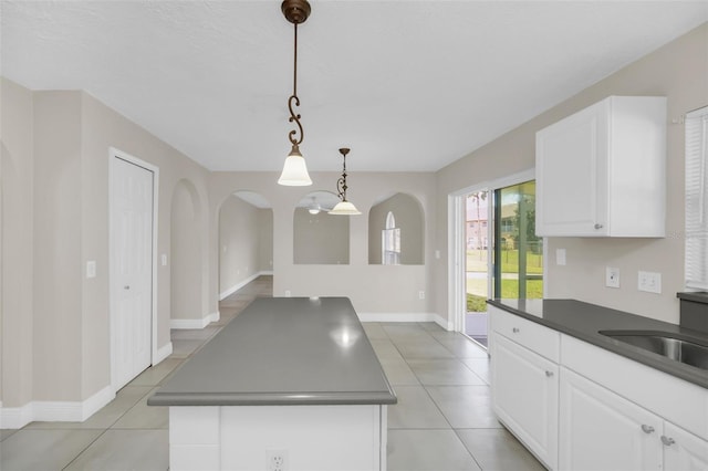 kitchen featuring pendant lighting, white cabinetry, a center island, and sink