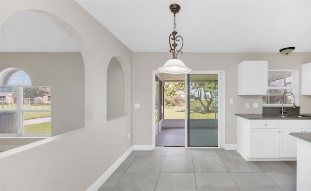 kitchen featuring white cabinetry, sink, hanging light fixtures, and light tile patterned floors