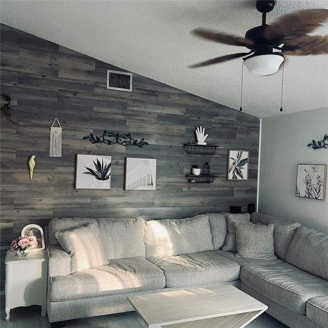 living room featuring ceiling fan, lofted ceiling, and a textured ceiling