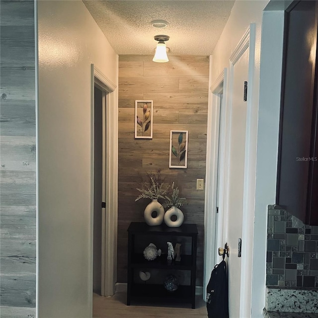 hall with a textured ceiling and wood walls