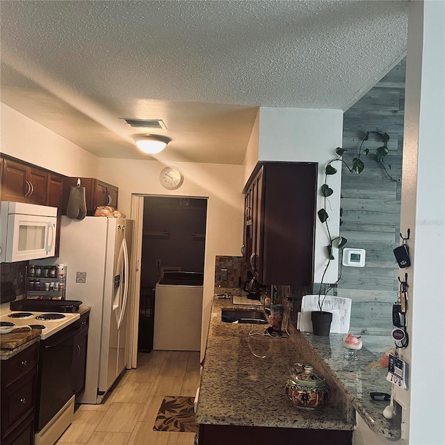 kitchen featuring electric stove, washer / clothes dryer, dark brown cabinets, and dark stone countertops