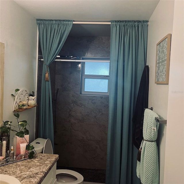 bathroom featuring vanity, a tile shower, and toilet