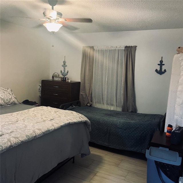 bedroom with ceiling fan, light hardwood / wood-style floors, and a textured ceiling