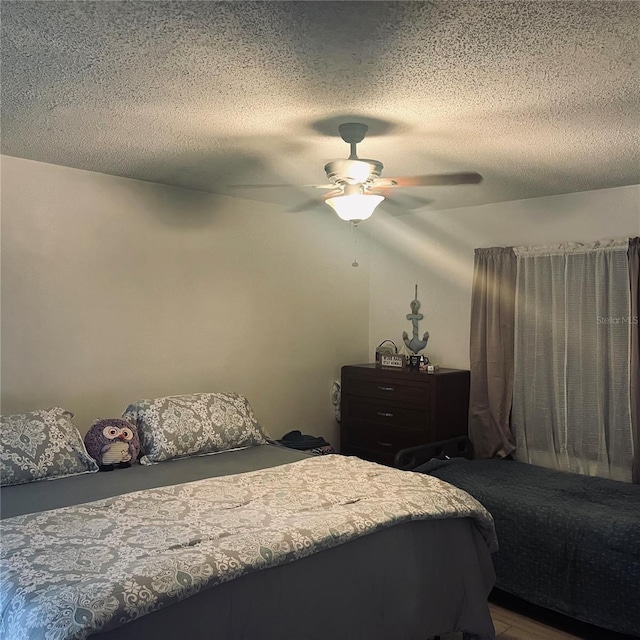 bedroom with ceiling fan, hardwood / wood-style floors, and a textured ceiling