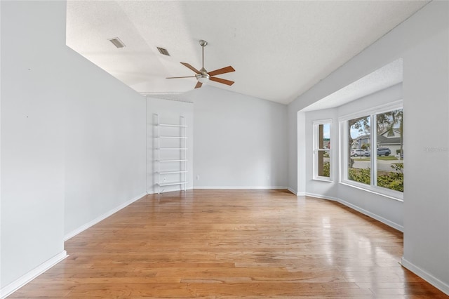 empty room featuring lofted ceiling, ceiling fan, a textured ceiling, and light wood-type flooring