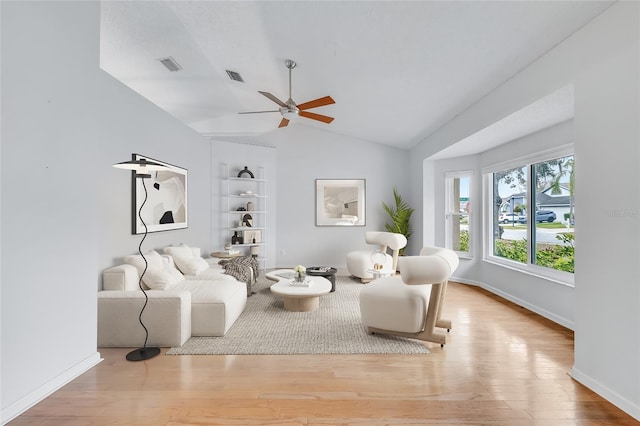 interior space with ceiling fan, built in features, vaulted ceiling, and light hardwood / wood-style flooring