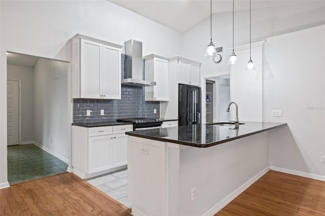 kitchen featuring white cabinetry, wall chimney exhaust hood, high end black refrigerator, and pendant lighting