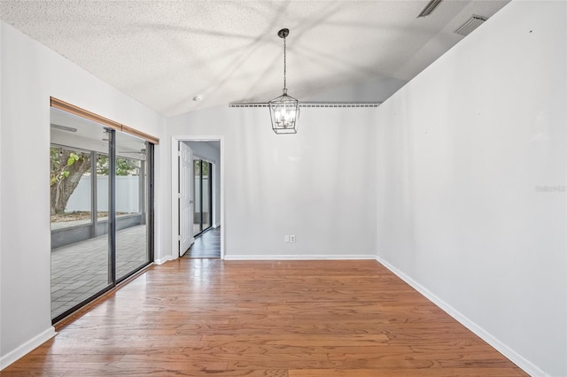 unfurnished dining area with wood-type flooring, a chandelier, a textured ceiling, and vaulted ceiling