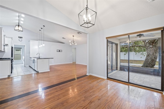 unfurnished living room with vaulted ceiling, sink, and light wood-type flooring