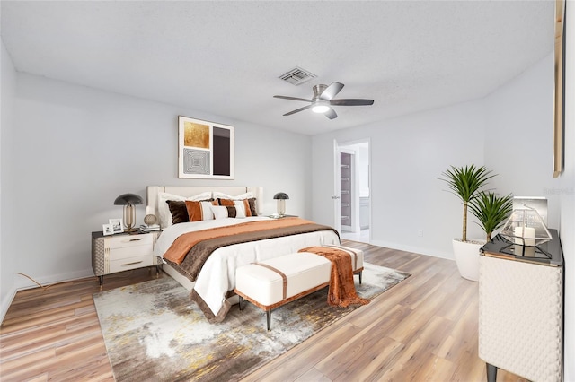 bedroom featuring ceiling fan, light hardwood / wood-style floors, and a textured ceiling