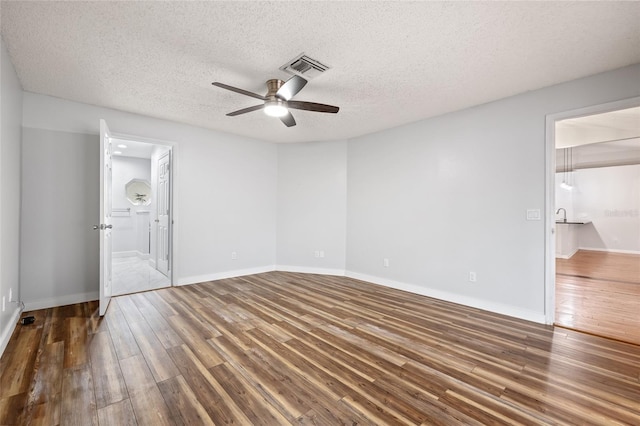 unfurnished bedroom with dark wood-type flooring, ceiling fan, ensuite bath, and a textured ceiling