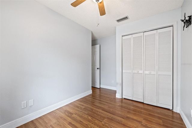 unfurnished bedroom with hardwood / wood-style flooring, ceiling fan, a closet, and a textured ceiling