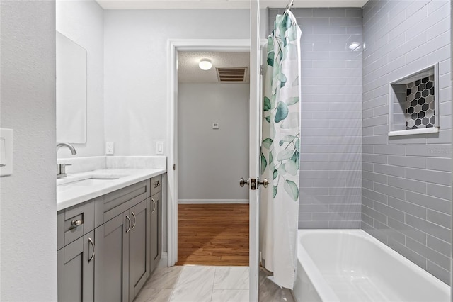 bathroom with shower / bath combo, vanity, and a textured ceiling