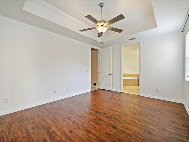 interior space featuring ceiling fan, connected bathroom, dark hardwood / wood-style flooring, and a tray ceiling