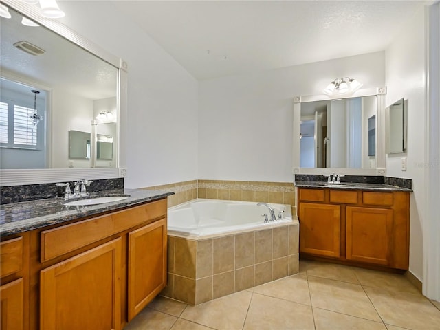 bathroom featuring tile patterned flooring, vanity, and a relaxing tiled tub