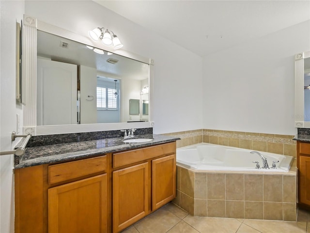 bathroom with tile patterned flooring, vanity, and tiled bath