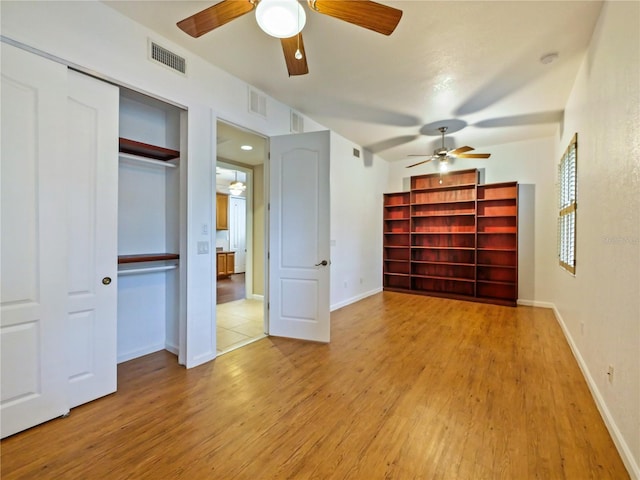 unfurnished bedroom with ceiling fan, light wood-type flooring, and a closet