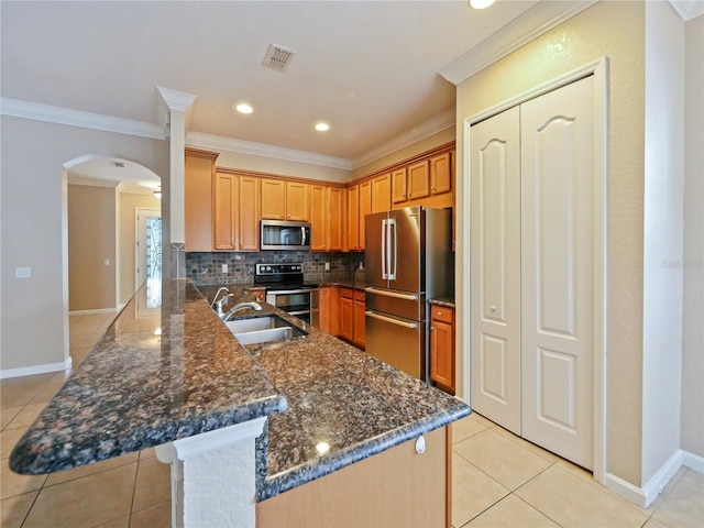 kitchen featuring sink, tasteful backsplash, appliances with stainless steel finishes, a kitchen breakfast bar, and kitchen peninsula