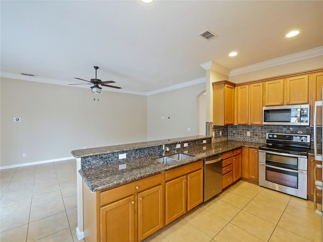 kitchen with dark stone countertops, sink, stainless steel appliances, and kitchen peninsula