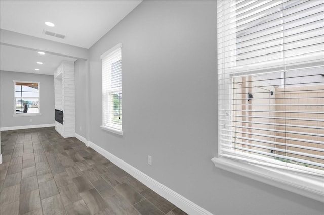 unfurnished living room with dark wood-type flooring and a large fireplace