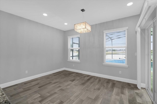 unfurnished dining area featuring a healthy amount of sunlight, dark wood-type flooring, and a chandelier