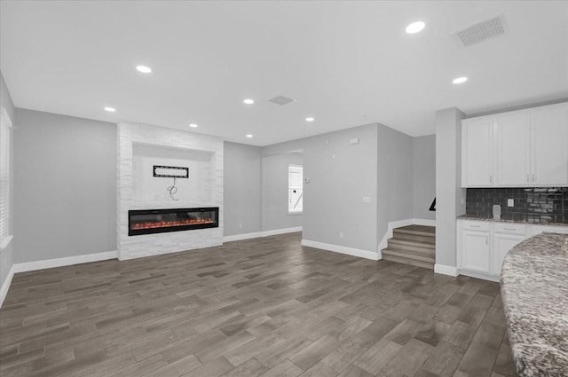 unfurnished living room with hardwood / wood-style flooring and a large fireplace