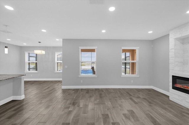 unfurnished living room featuring a stone fireplace and dark hardwood / wood-style flooring