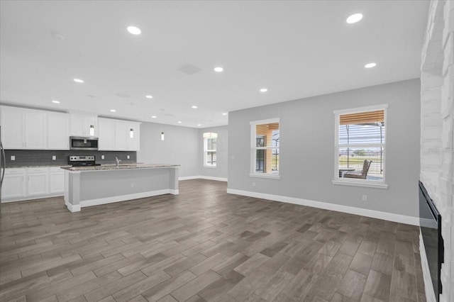 kitchen with white cabinetry, hardwood / wood-style flooring, an island with sink, and appliances with stainless steel finishes