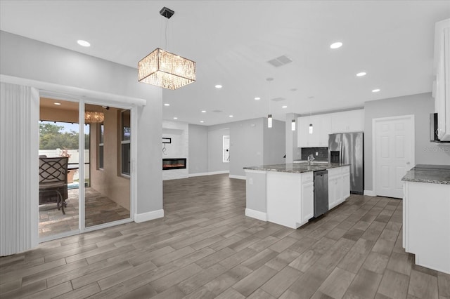 kitchen featuring pendant lighting, white cabinetry, stainless steel appliances, and an island with sink