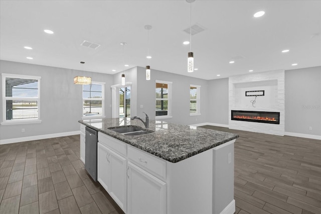 kitchen with sink, dishwasher, hanging light fixtures, white cabinets, and a center island with sink