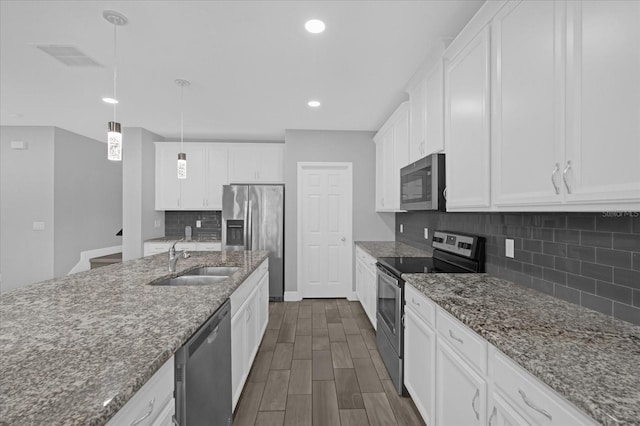 kitchen featuring sink, appliances with stainless steel finishes, hanging light fixtures, white cabinets, and dark stone counters