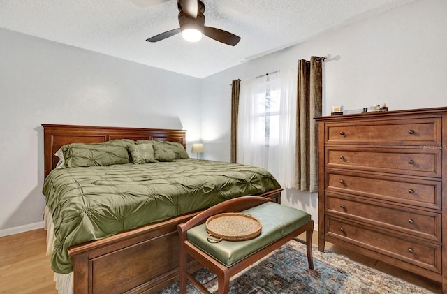 bedroom with ceiling fan, a textured ceiling, and light hardwood / wood-style flooring