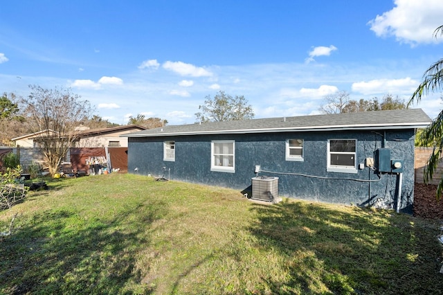 rear view of property featuring central AC and a lawn