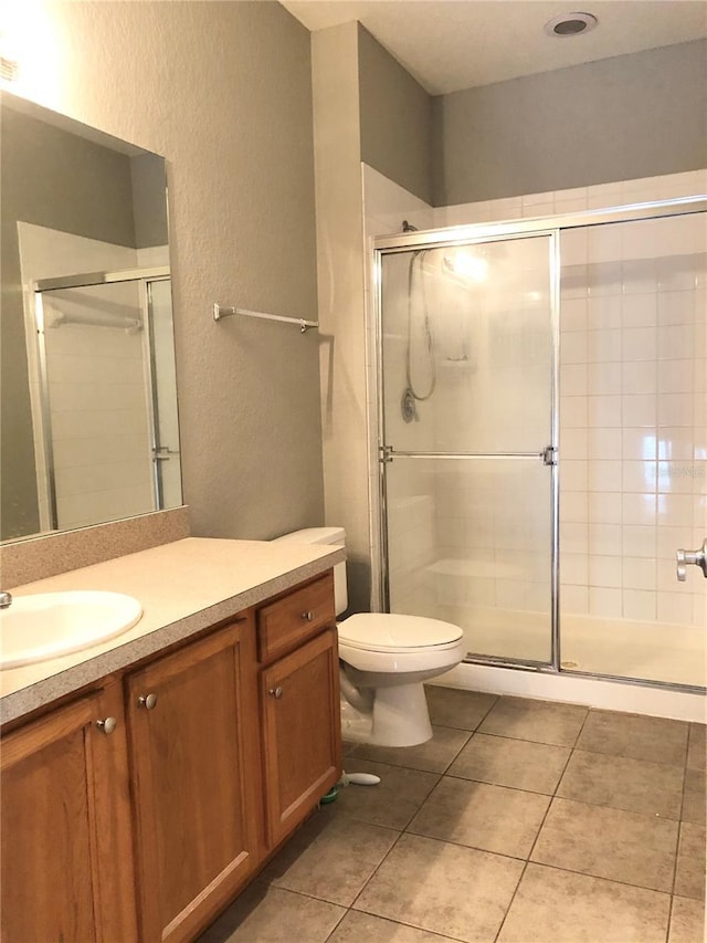 bathroom with walk in shower, tile patterned floors, vanity, and toilet