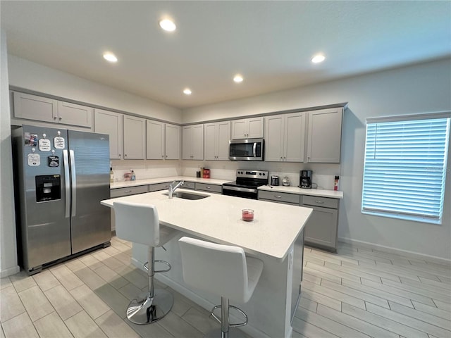 kitchen featuring an island with sink, appliances with stainless steel finishes, sink, and gray cabinetry