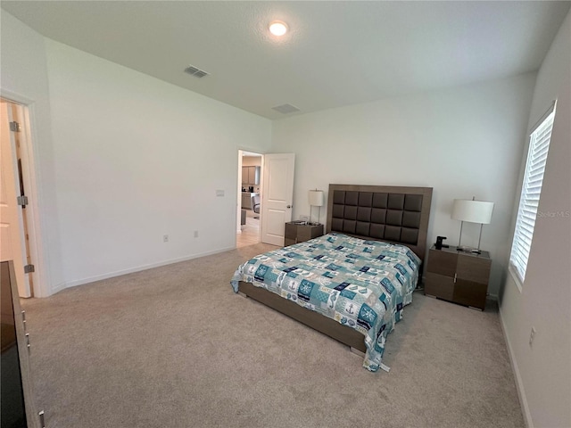 bedroom with washer / dryer and light colored carpet