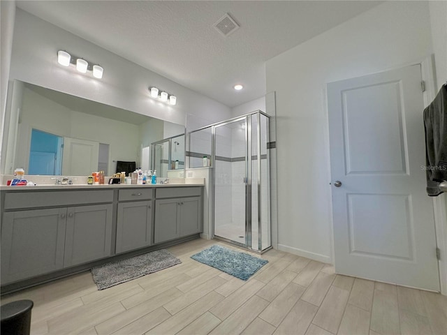 bathroom with walk in shower, vanity, and a textured ceiling