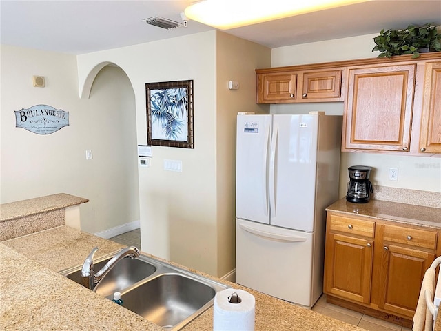 kitchen featuring sink, light tile patterned floors, and white fridge